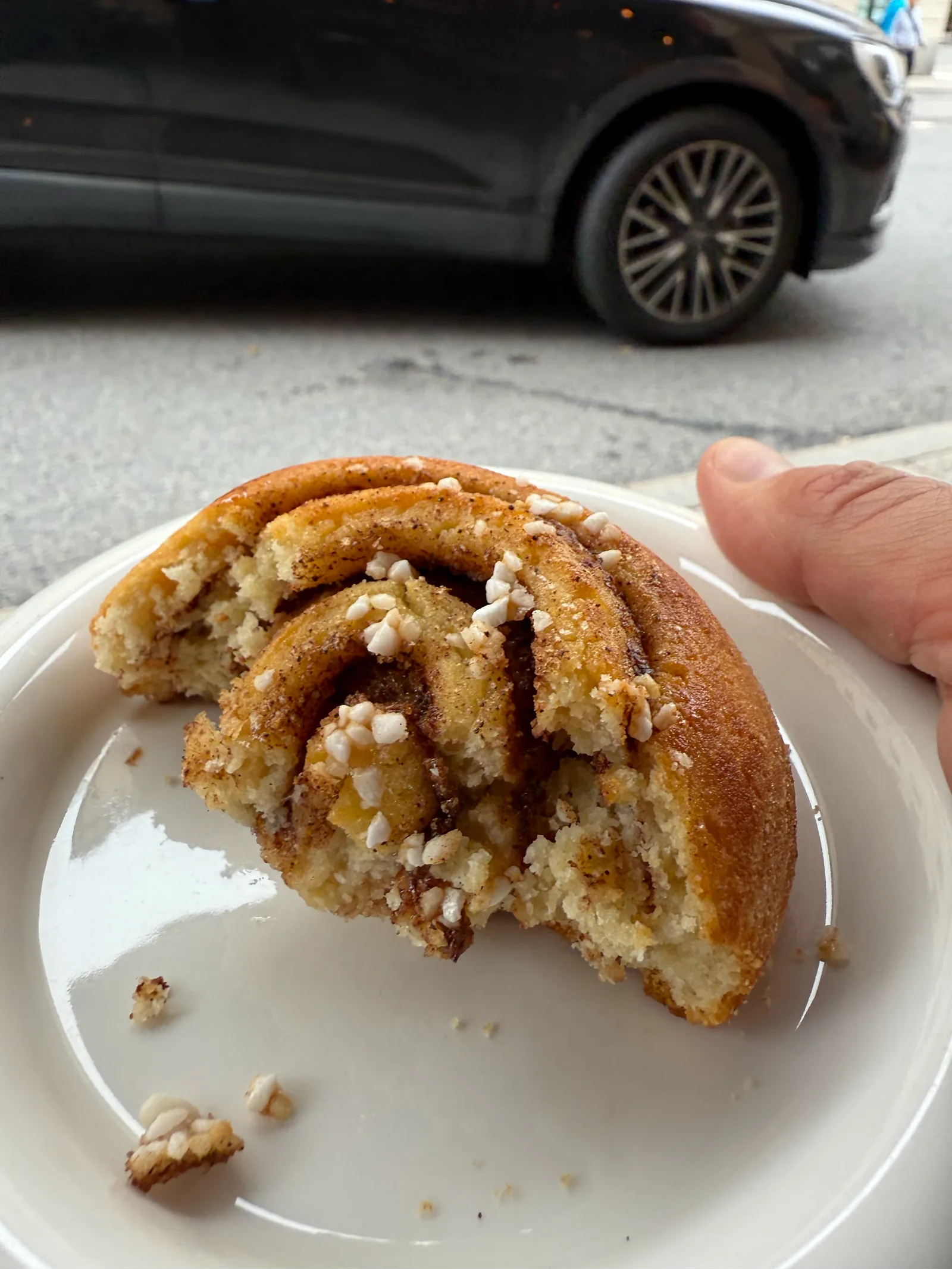 Angebissene Kanelbulle mit Hagelzucker auf einem weißen Teller