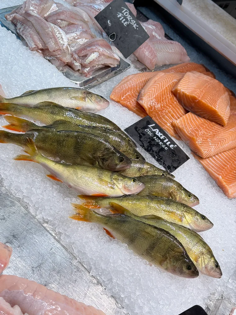 Fischtheke mit Flussbarschen auf Eis, daneben Lachsfilet und Dorsch