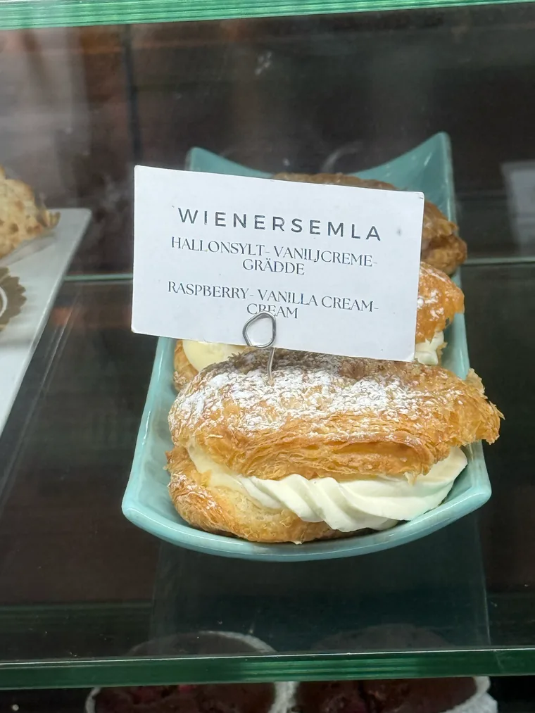 Wienersemla in einer Kühlvitrine, Schild auf Schwedisch und Englisch