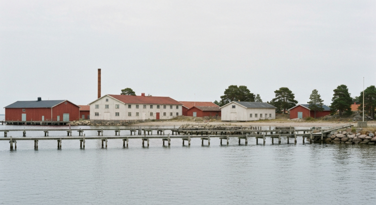 Hafen von Gustavsberg mit Holzstegen und alten Backstein- und Holzfabrikgebäuden an einer ruhigen Ostseebucht